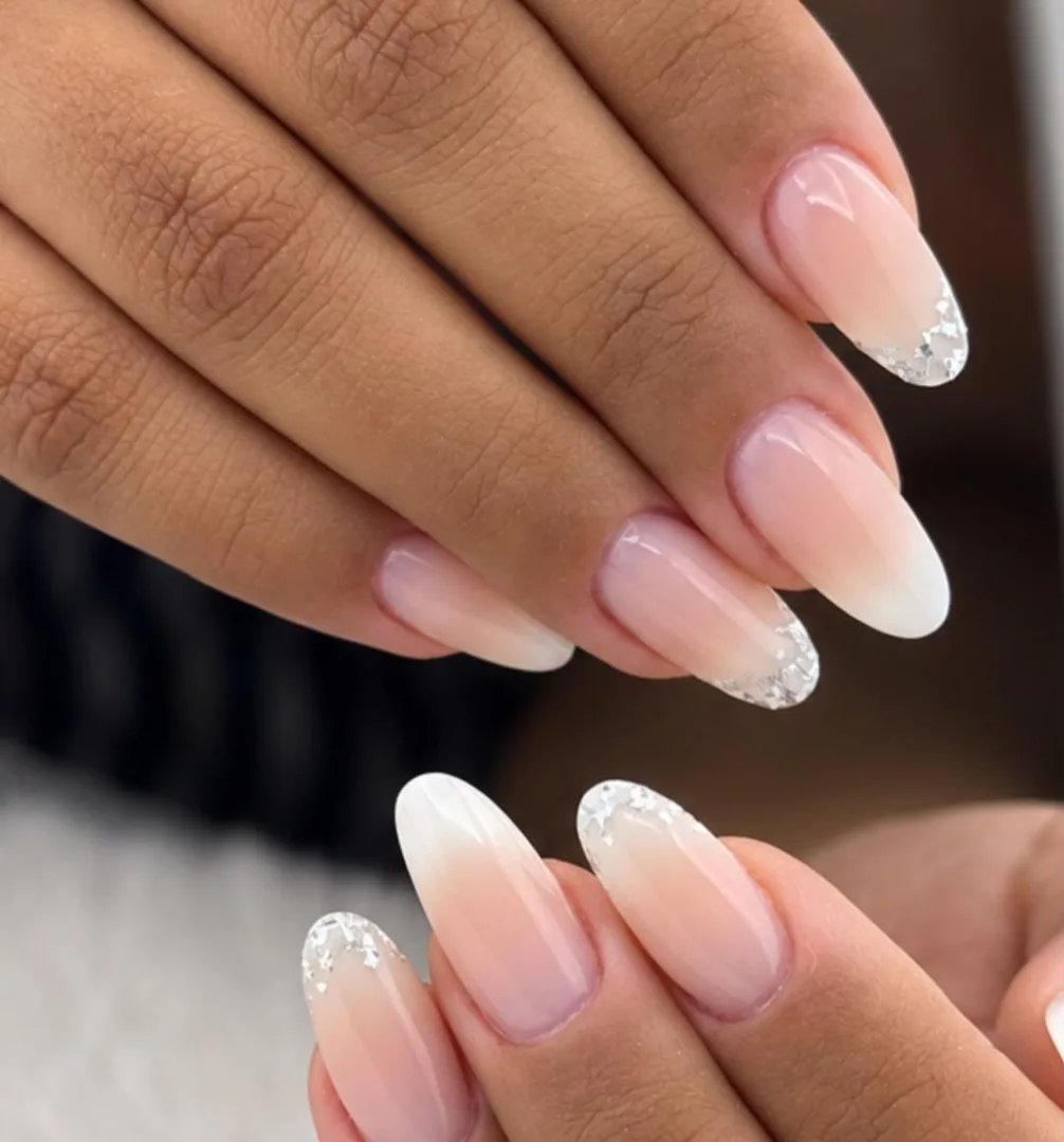Unhas amendoadas em degradê nude com pontas de glitter prateado